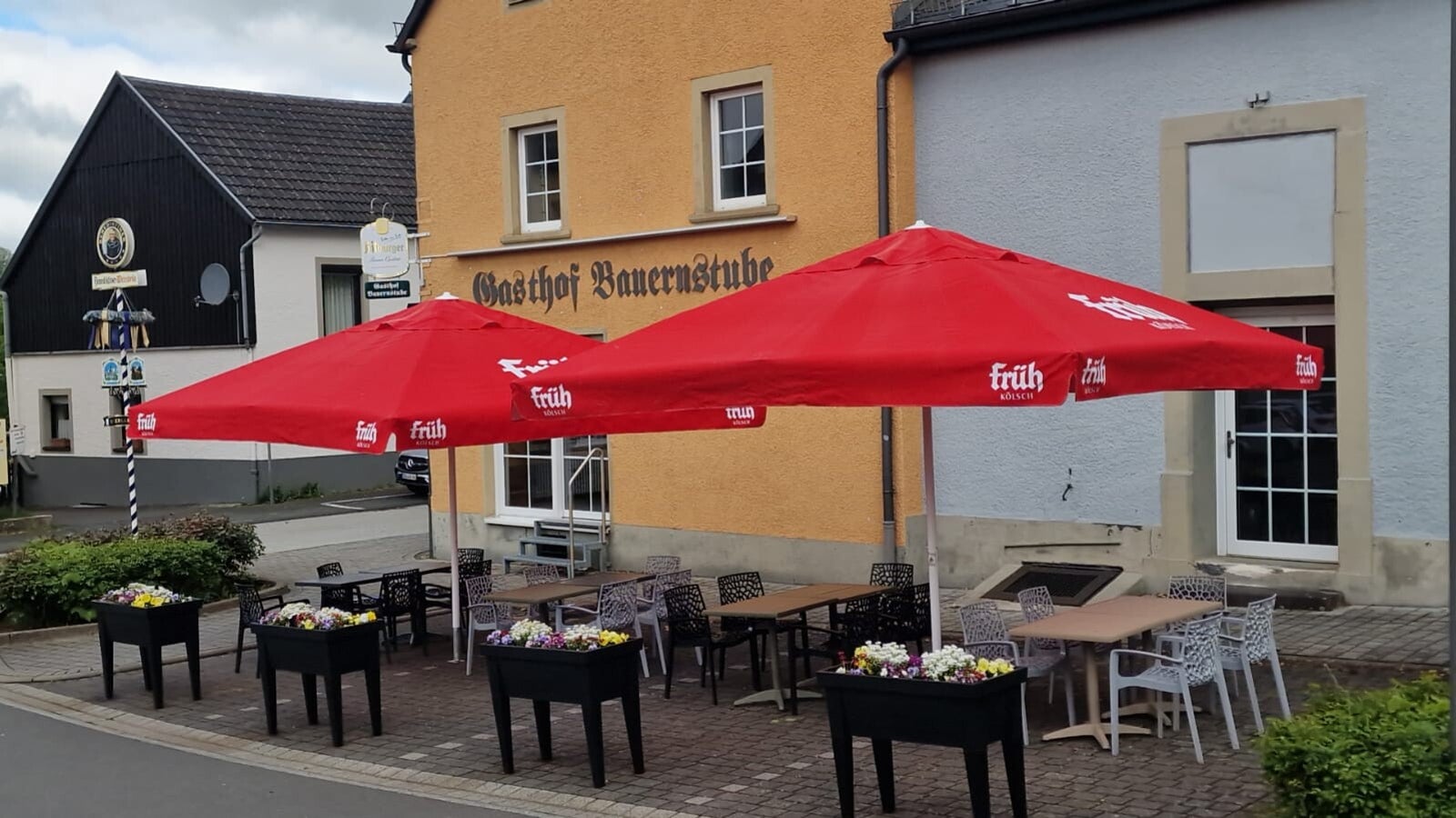 Terrasse der Bauernstube Hillesheim mit roten Sonnenschirmen